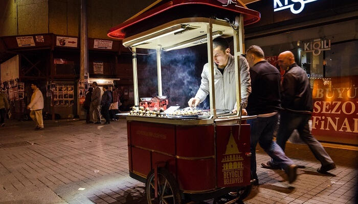 يقوم أحد بائعي طعام الشارع العاديين بطهي الأطباق المحلية على عربة طعام محمولة