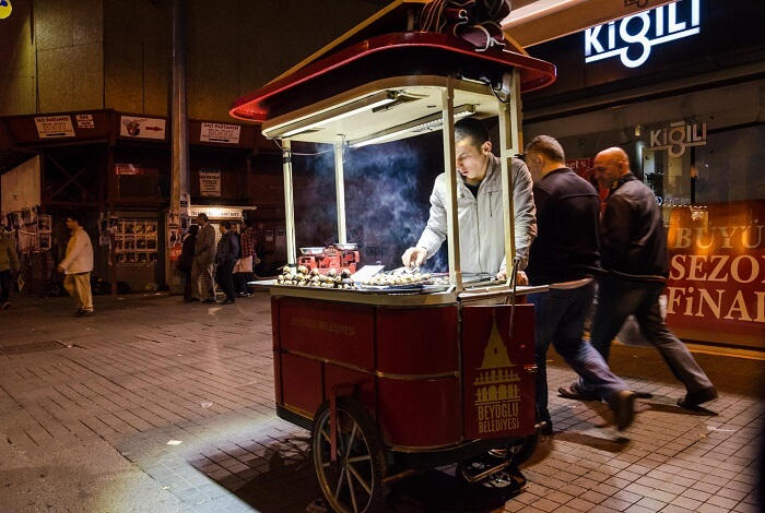 يقوم أحد بائعي طعام الشارع العاديين بطهي الأطباق المحلية على عربة طعام محمولة